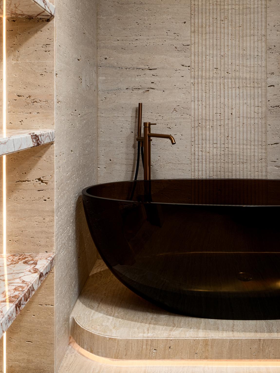Bathing suite with a smoked resin tub set into a travertine plinth