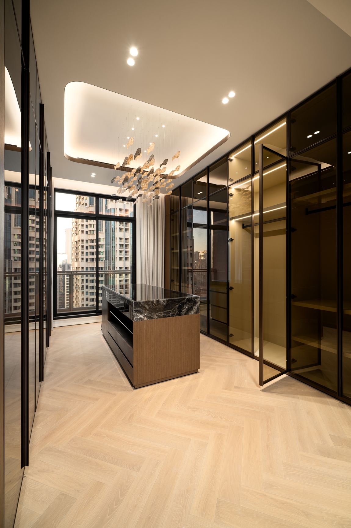 Dressing room with bronze glass wardrobes and a herringbone oak floor