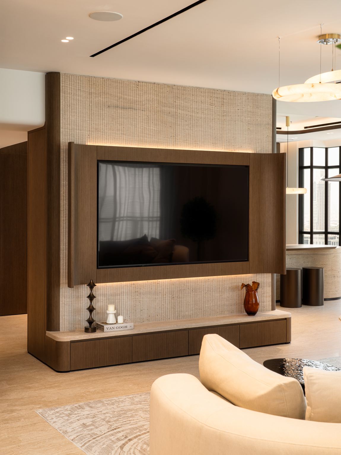 Living room with a fluted travertine media wall and concealed lighting